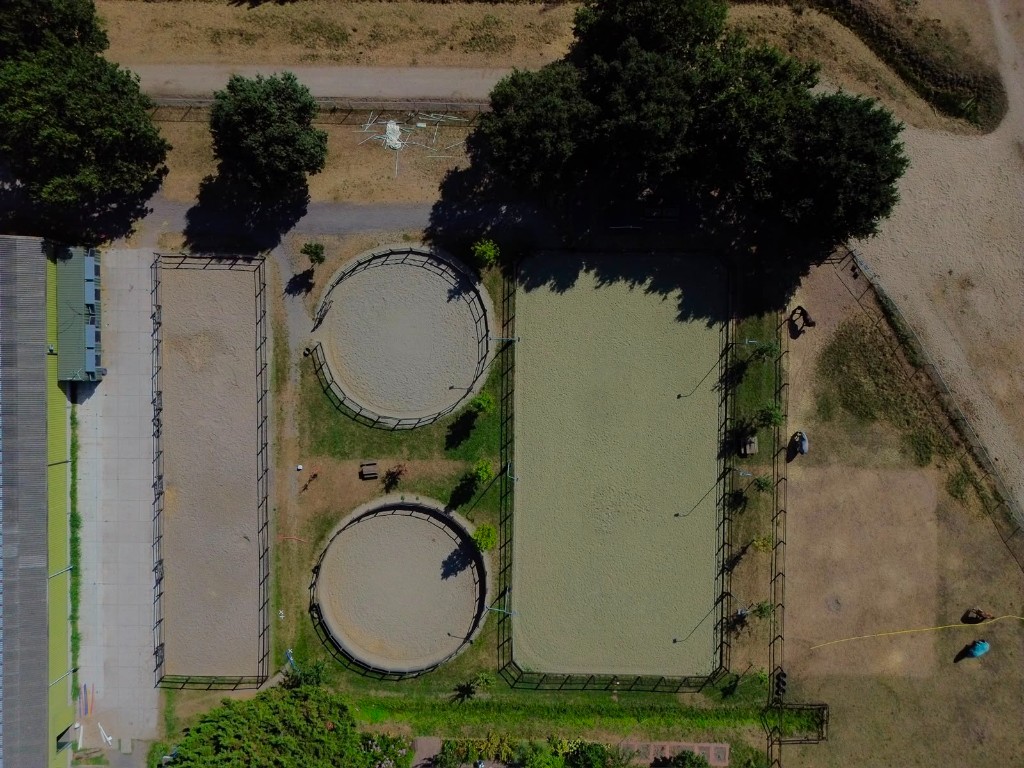 Dronefoto van buitenbakken en longeercirkels van De Barendrechtse Manege van bovenaf.